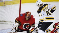 Gólman Calgary David Rittich zasahuje ped Dantonem Heinenem z Bostonu.