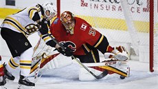 Gólman Calgary David Rittich zasahuje proti stele  Brada Marchanda z Bostonu.