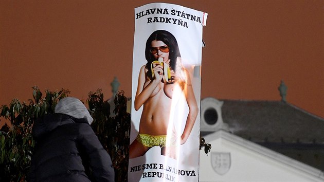 Účastník protestního pochodu instaluje plakát s portrétem Ficovy asistentky Márii Troškové na plot bratislavského úřadu vlády. (2. března 2018)