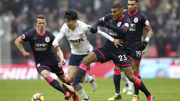 DO ANCE. Son Hung-min, fotbalista Tottenhamu, se probj do ance mezi dvma protihri z  Huddersfieldu.
