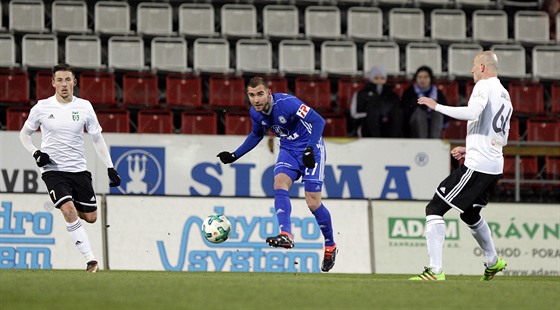 Olomoucký Martin Sladký (v modrém uprosted) odehrává mí ped blíící se...