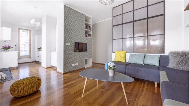 Kuchyň s obývacím pokojem propojuje jednolitý dřevěný dekor podlahy. Prostor zjemňují odstíny zelenkavé tapety a výmalba v nejsvětlejším barevném tónu tapety a stejně tak decentní barevné odstíny sedacího nábytku a konferenčního stolku.