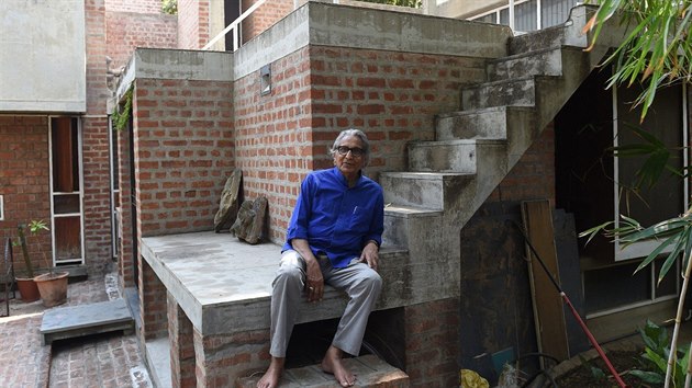 Architekt Balkrišna Doši sedí na schodech v bytovém komplexu v Ahmadábádu. 