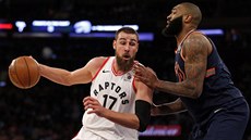 Jonas Valaniunas (v bílém) z Toronto Raptors naráí do Kyla OQuinna z New...