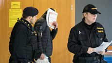 Policisté odvádjí obvinného soudce Ivana Elischera (v kapuci) od praského...