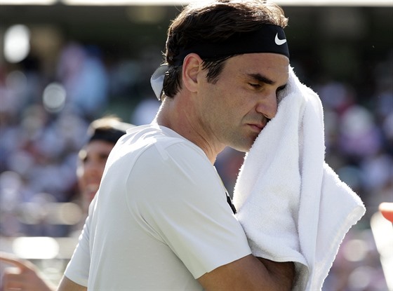 Nespokojený Roger Federer schovává tvá do runíku a utírá si pot.