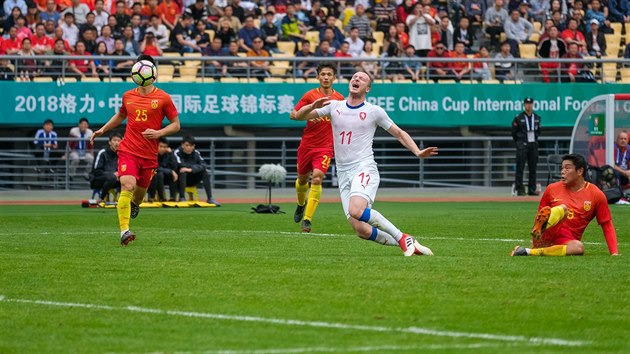 Český útočník Michael Krmenčík padá ve vápně po zákroku čínského obránce v utkání China Cupu.