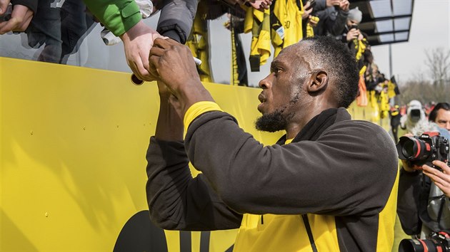 Usain Bolt se podepisuje fanoukm po trninku s  fotbalisty bundesligovho Dortmundu.