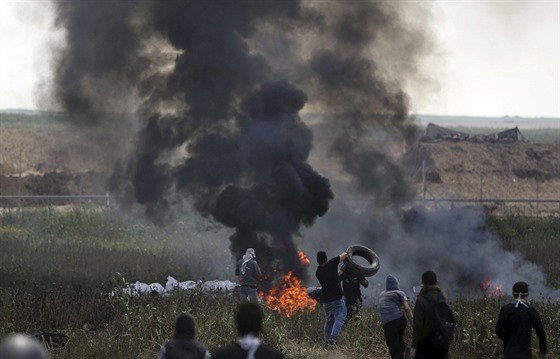 erný kou stoupá z hoících pneumatik, které Palestinci pálí v hraniním pásmu...