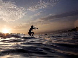 VEERNÍ SURFING. Surfaka sjídí vlnu pi západu slunce v peruánské Lim.