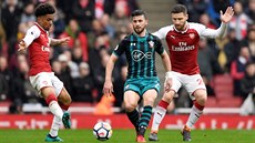 Shane Long ze Southamptonu (uprosted) se proplétá mezi Reissem Nelsonem...