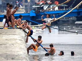 ŠPINAVÉ OSVĚŽENÍ. Filipínská dívka ve vedru skáče do znečištěné vody Manilské...