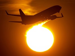 VZHŮRU ZA SLUNCEM. Letadlo vzlétá při západu slunce z ranveje letiště v...