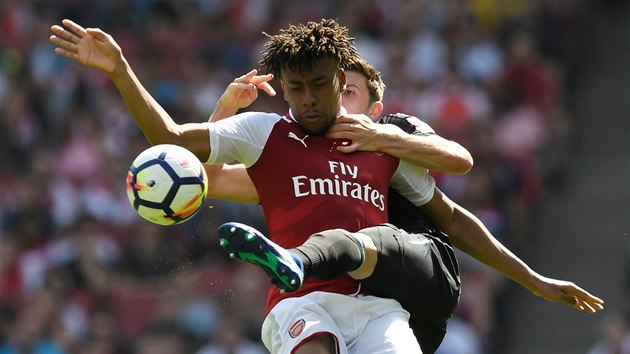 Alex Iwobi z Arsenalu si snaží pokrýt míč před dotírajícím Declanem Ricem z West Hamu.