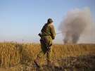 Izraelský voják jde smrem k zemdlské pd, kterou zapálil drak s kusem...