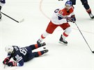 Americký hokejista Patrick Kane (v modrém) padá na led. Kolem projídí ve...