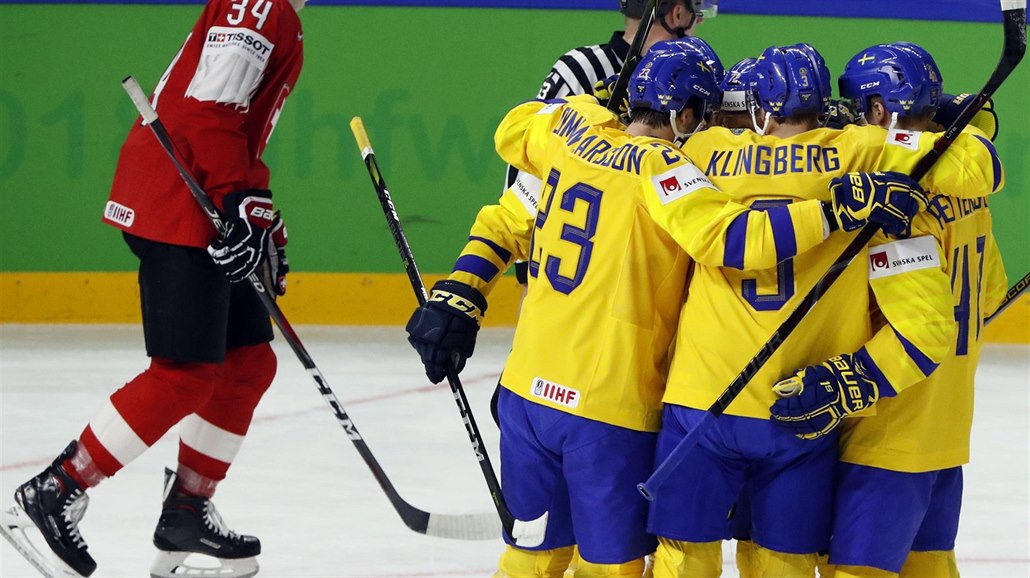 Švédští hokejisté (ve žlutém) se radují z branky do sítě Švýcarska.