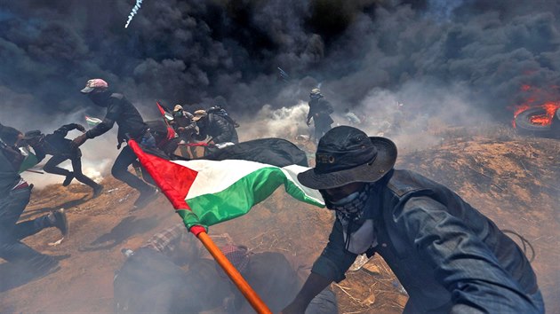 NEPOKOJE NA HRANICI. Palestinští demonstranti v Pásmu Gazy spěchají do úkrytu před izraelskou střelbou a slzným plynem během protestů na hranici s Izraelem proti přesunu americké ambasády do Jeruzaléma.