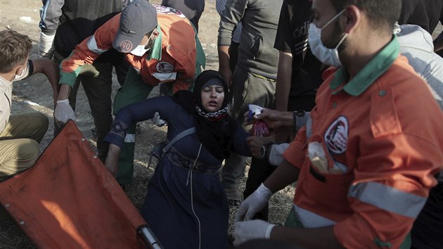 Palestinští demonstranti se snaží naložit zraněnou ženu na nosítka (15. května 2018).