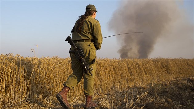 Izraelský voják jde směrem k zemědělské půdě, kterou zapálil drak s kusem hořící látky (15. května 2018).