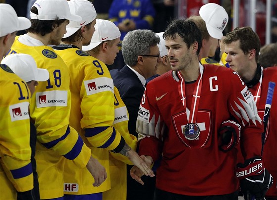 Švýcarský kapitán Raphael Diaz (v červeném) podává ruku švédským hokejistům,...