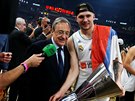 Luka Dončič z Realu Madrid drží trofej pro vítěze Euroligy, naklání se k němu...
