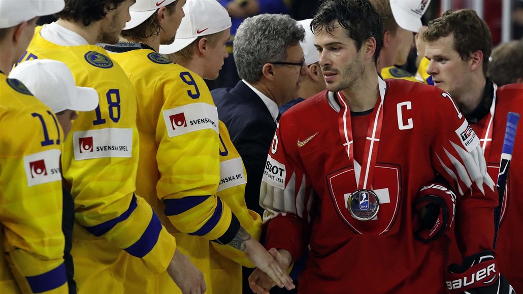 Švýcarský kapitán Raphael Diaz (v červeném) podává ruku švédským hokejistům,...