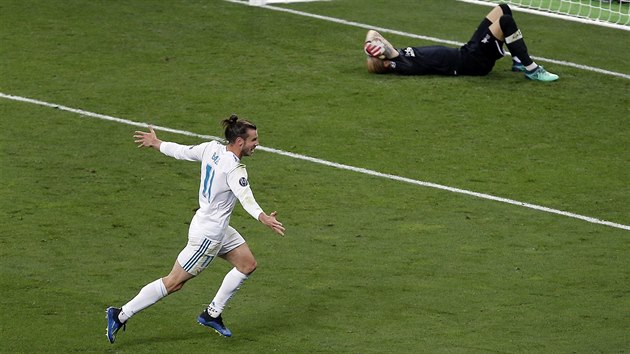 Gareth Bale (v bílém) střílí třetí gól Realu Madrid ve finále Ligy mistrů, brankář Liverpoolu Loris Karius se na zemi stydí za další hrubku.
