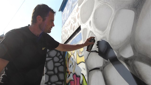 Jakub Menk dokonuje ob graffiti na zdi v jihlavsk Bezruov ulici. S prac mu obas pomhaj ptel.