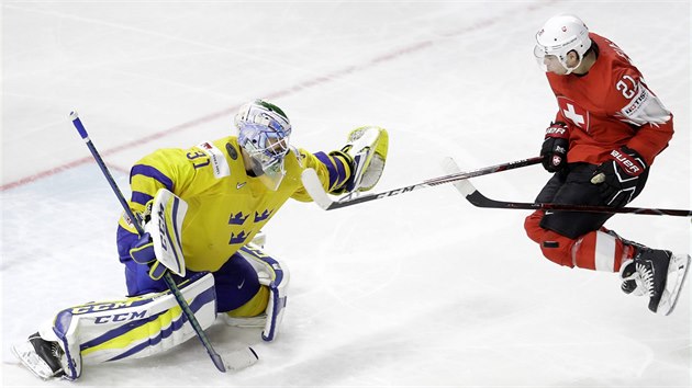 Švýcarský útočník Kevin Fiala skáče před švédským gólmanem Andersem Nilssonem.