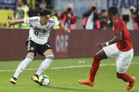 Německý fotbalista Mesut Özil kličkuje před rakouským Davidem Alabou