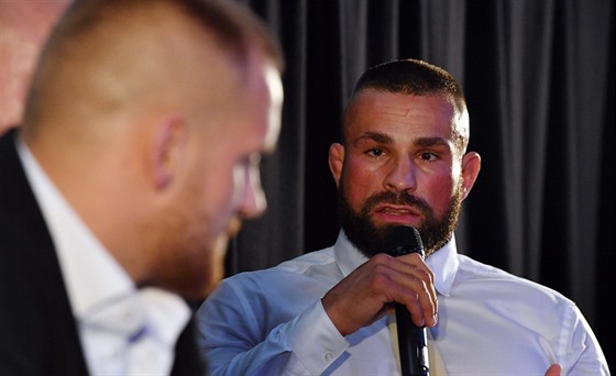 Bojovník MMA Karlos Vémola drží mikrofon a mluví na svého vyzyvatele Patrika...