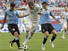 Ruský hromotluk Arjom Dzjuba se prodírá mezi hrái Uruguaye.
