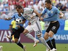 Ruský útočník Arťjom Dzjuba se prodírá mezi dvěma uruguayskými bránícími hráči.