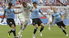 Ruský hromotluk Arjom Dzjuba se prodírá mezi hrái Uruguaye.
