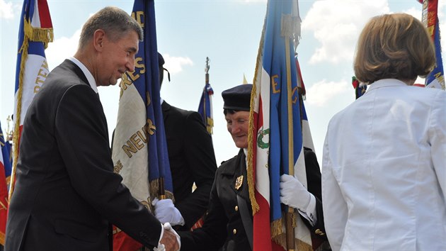 Premiér Andrej Babiš se na pietním aktu u památníku nedaleko Darney zdraví s vlajkonoškou jedné z vojenských zástav (30. června 2018)