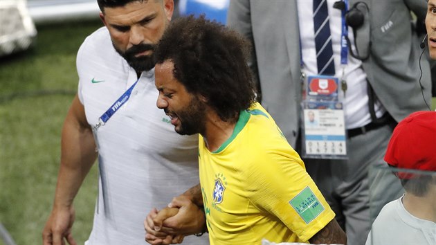 Brazilský obránce Marcelo za doprovodu týmového lékaře opouští hřiště během utkání proti Srbsku.