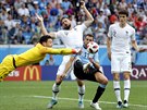 Francouzský brankář Hugo Lloris boxuje míč před útočníkem Uruguaye Christhianem...