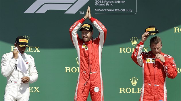 Uprosted stoj vtz Velk ceny Britnie formule 1 Sebastian Vettel, v bl kombinze druh Lewis Hamilton, vpravo stoj tet Kimi Rikknen.