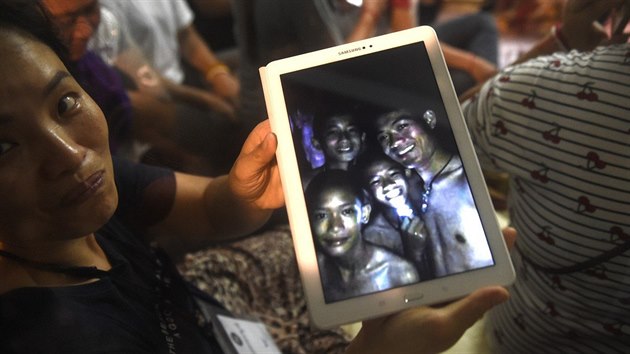 Šťastná žena ukazuje na tabletu aktuální fotku chlapců v jeskyni, kterou pořídili záchranáři. Dvanáct fotbalistů s trenérem se podařilo najít po devíti dnech.