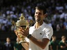 Potvrté. Srbský tenista Novak Djokovi se tí s trofejí pro ampiona...