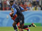 Francouzský záloník Paul Pogba se snaí utéct belgickému protivníkovi Moussovi...