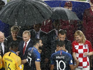 Zatímco ruský prezident Vladimir Putin se před deštěm schovává pod deštníkem,...