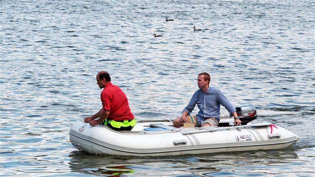 Petr Kvapil (v červené košili) s kolegou Vojtěchem Stejskalem z firmy na ultrazvukovou likvidaci sinic v úterý na Velkém rybníku kontrolovali pontony s ultrazvukovými vysílači a odebírali vzorky vody. (17.7.2018)