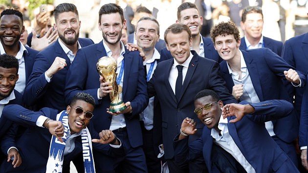 Francouzský brankář Hugo Lloris hrdě pózuje s trofejí pro mistry světa, vpravo od něj je prezident Emmanuel Macron.