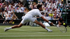Srbský tenista Novak Djokovi se natahuje po míku ve tvrtfinále Wimbledonu.