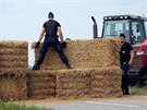 Policisté se snaí odklidit balíky slámy.