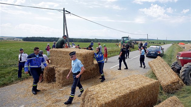 Policist se sna odklidit balky slmy, ktermi farmi zatarasili cestu 16. etapy Tour.