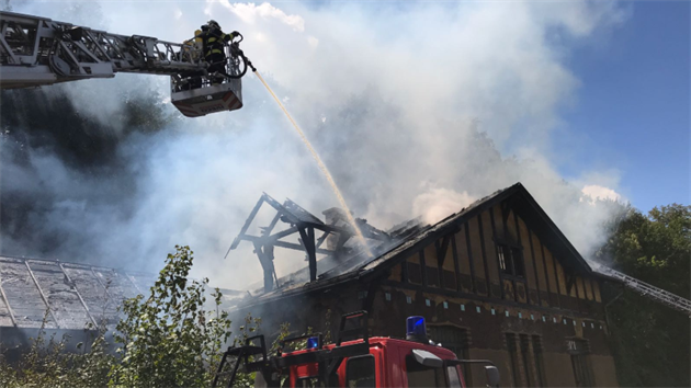 Hasiči zasahují v pražské Libocké ulici při požáru střechy jednoho z tamních domů (25.7.2018)