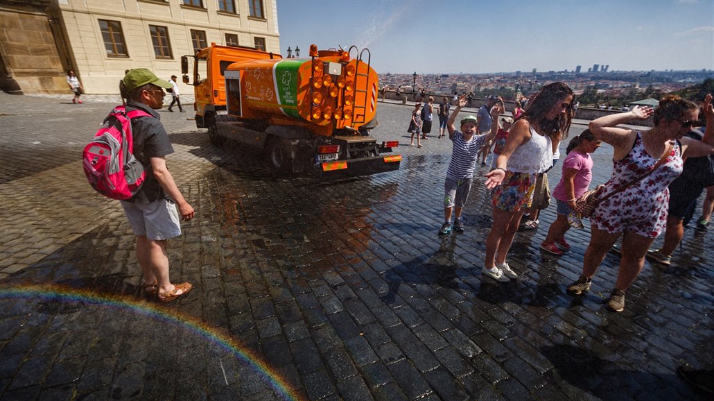 Na Hradčanském náměstí se návštěvníci chladí u kropicího vozu. (31. července...